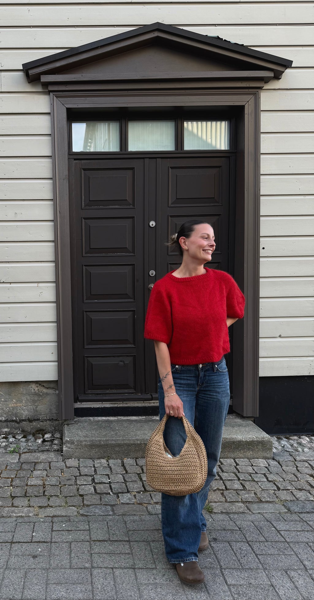 Boxy Shortsleeve i rødt, helfigur foran en mørk dør