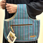 Woven Knit&Go håndvevd strikkeveske i turkis, båret over armen